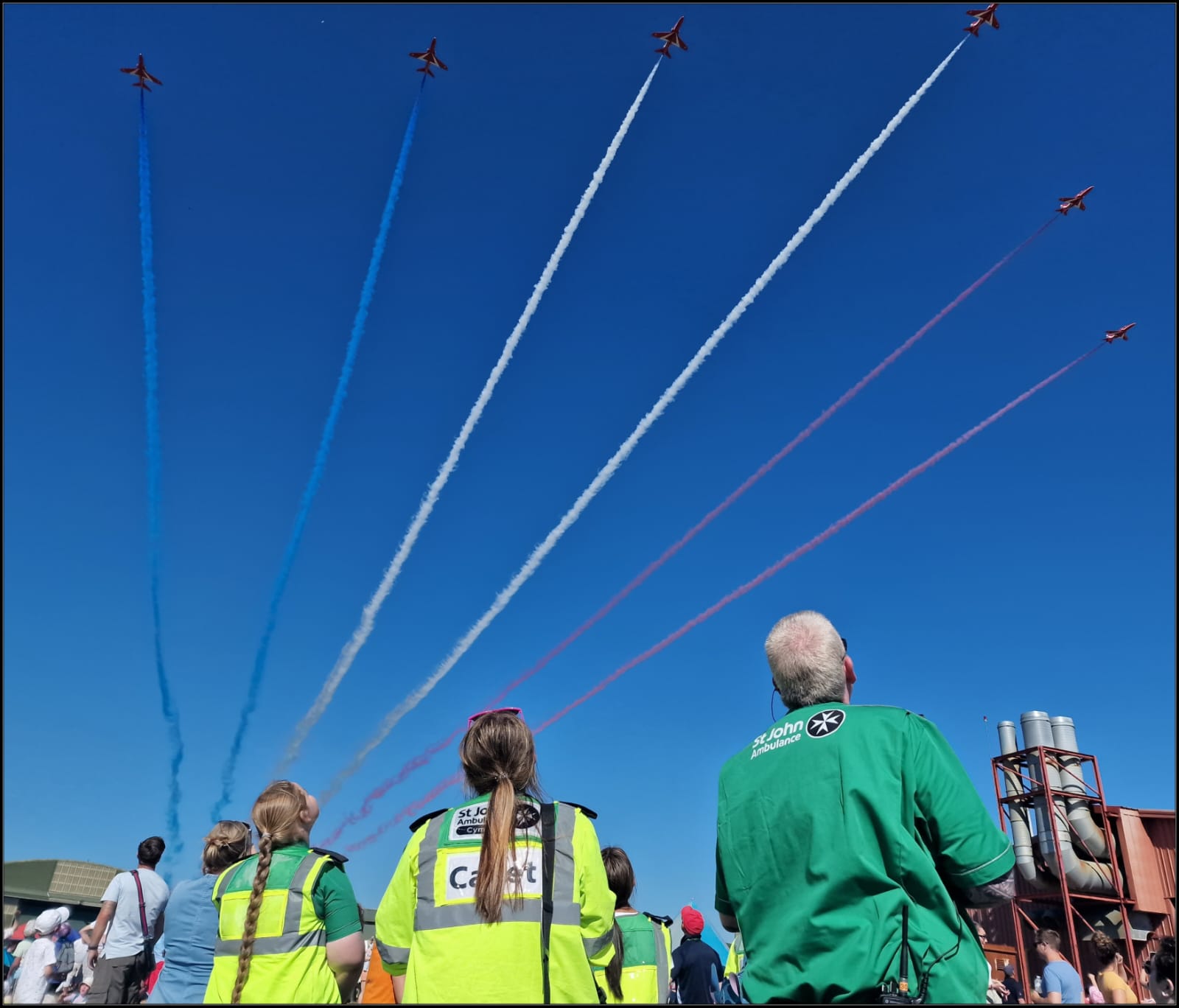 A group of people watching airplanes flying in the skyDescription automatically generated with low confidence