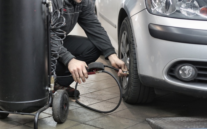 A person fixing a car tireDescription automatically generated with low confidence