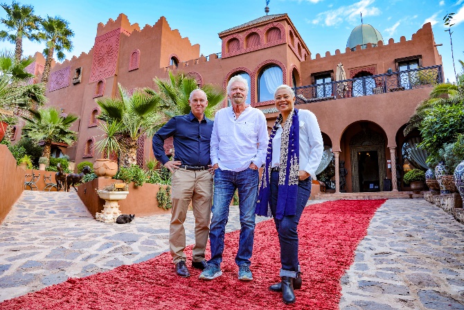 A group of people standing in front of a red carpetDescription automatically generated