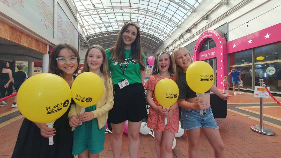 A group of girls holding yellow balloonsDescription automatically generated