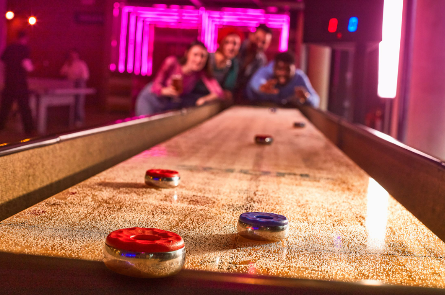 A group of people playing shuffleboardDescription automatically generated