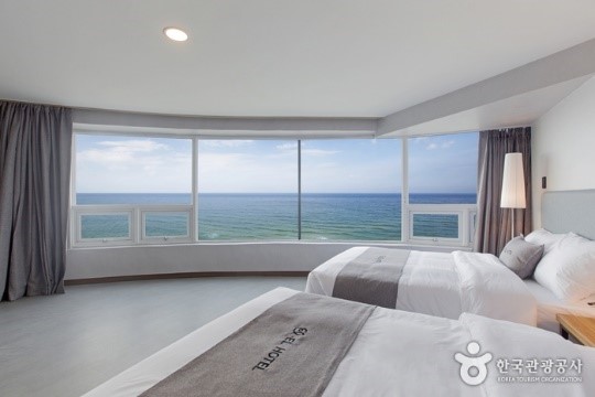 A room with two beds and a large window overlooking the oceanAI-generated content may be incorrect.