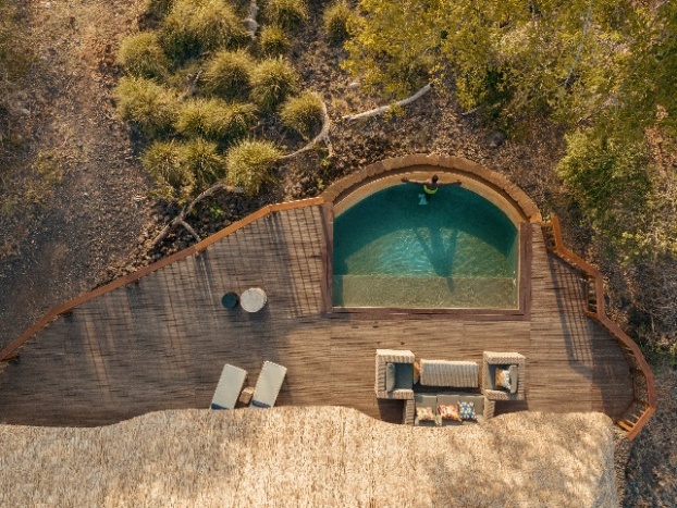 A pool and a deck with a chair and a tableDescription automatically generated with medium confidence