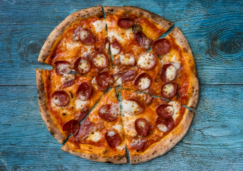 A pepperoni pizza on a blue TableDescription automatically generated