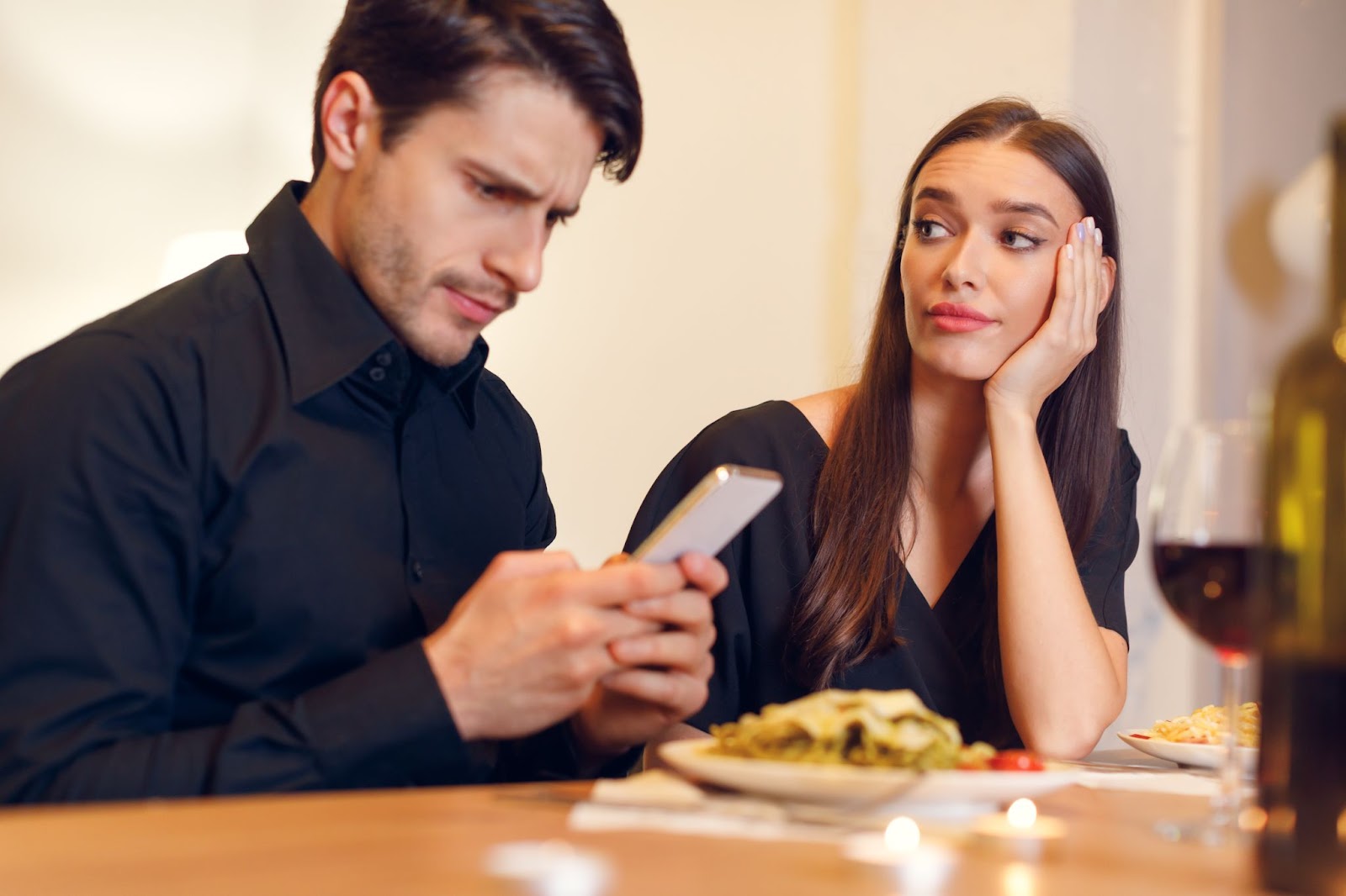 A person looking at a phone while a person looks at herDescription automatically generated