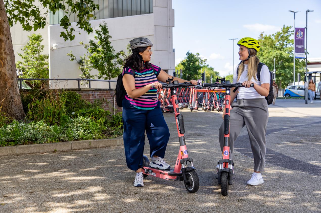 Two female Voi e-scooter riders