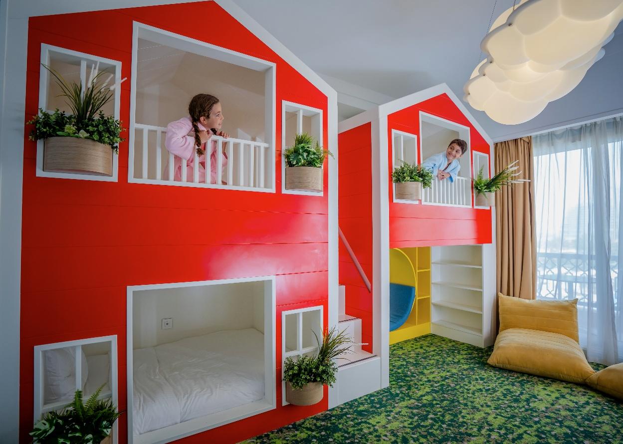 A kids in a room with a red and white houseAI-generated content may be incorrect.